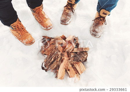 Two people stand in the snow near campfire 29333661