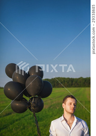 man in white shirt with black balloons in field man in white shirt with black balloons in field 29338685