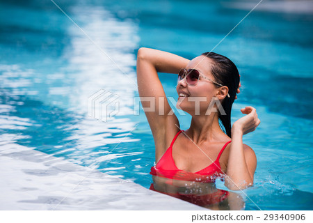 Woman wearing red swimsuit and sunglasses sitting Woman wearing red swimsuit and sunglasses sitting 29340906