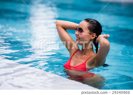 Woman wearing red swimsuit and sunglasses sitting Woman wearing red swimsuit and sunglasses sitting 29340908