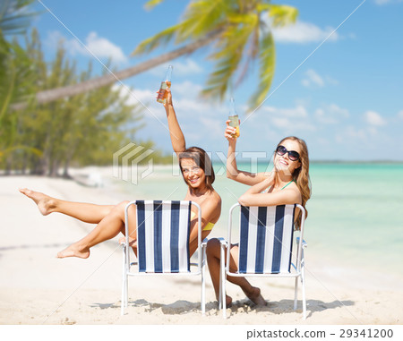 happy young women with drinks sunbathing on beach happy young women with drinks sunbathing on beach 29341200