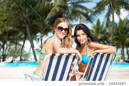 happy women sunbathing in chairs on summer beach happy women sunbathing in chairs on summer beach 29341687