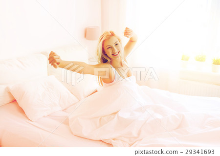 young woman stretching in bed at home bedroom young woman stretching in bed at home bedroom 29341693