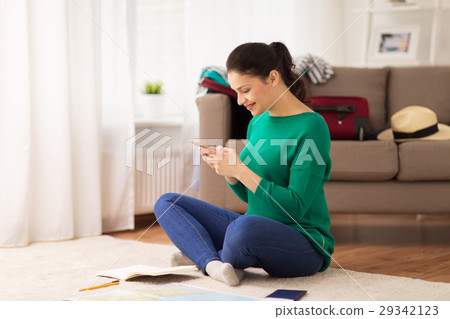 woman with smartphone and travel map at home 29342123