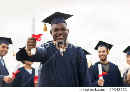 happy students in mortar boards with diplomas 29342582