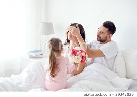 happy girl giving flowers to mother in bed at home happy girl giving flowers to mother in bed at home 29342826