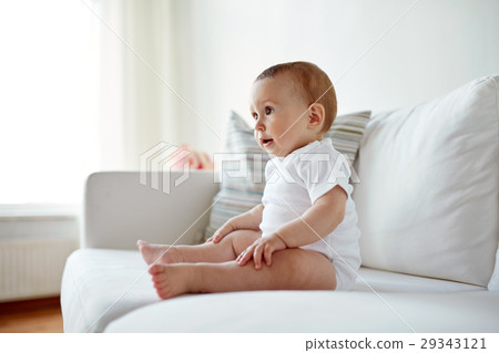 happy baby boy or girl sitting on sofa at home 29343121