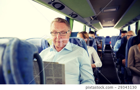 happy senior man reading newspaper in travel bus 29343130