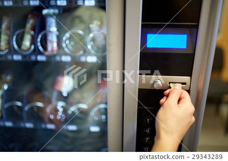 hand inserting euro coin to vending machine slot 29343289
