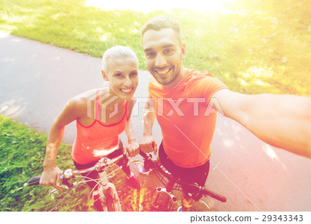 couple with bicycle taking selfie outdoors 29343343