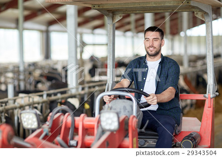 man or farmer driving tractor at farm 29343504