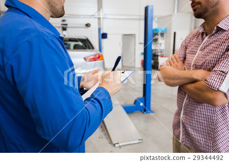 auto mechanic with clipboard and man at car shop 29344492