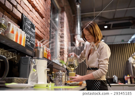 woman or barmaid cooking smoothie at vegan cafe woman or barmaid cooking smoothie at vegan cafe 29345185