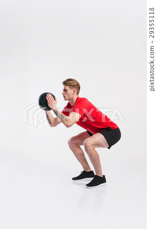 Fitness man holding medicine ball, doing squat Fitness man holding medicine ball, doing squat 29355118