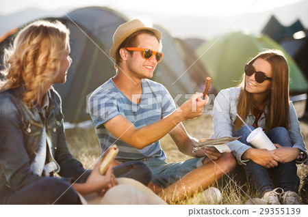 Teenagers sitting on the ground in front of tents Teenagers sitting on the ground in front of tents 29355139