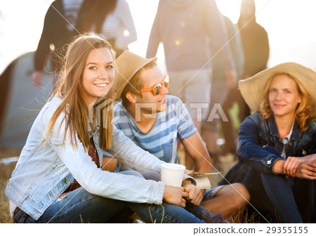 Teenagers sitting on the ground in front of tents Teenagers sitting on the ground in front of tents 29355155