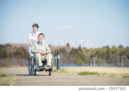 Senior male riding a wheelchair and a caregiver Senior male riding a wheelchair and a caregiver 29357162