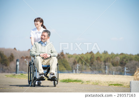 Senior male riding a wheelchair and a caregiver Senior male riding a wheelchair and a caregiver 29357163
