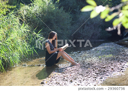 girl reading a book in the forest 29360736