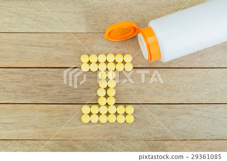 Yellow pills forming shape to I alphabet on wood 29361085