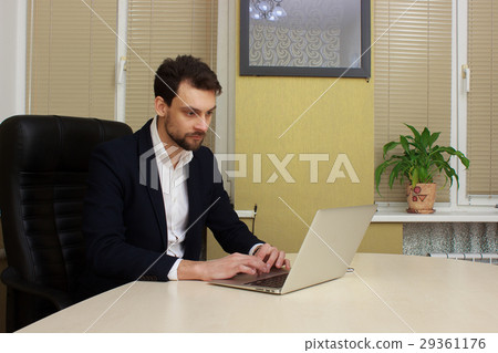 young businessman sitting behind his desk with young businessman sitting behind his desk with 29361176