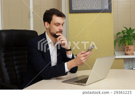 Young happy businessman smiling while reading his 29361225