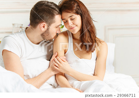 Young adult heterosexual couple lying on bed in Young adult heterosexual couple lying on bed in 29366711