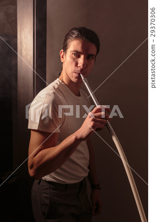 Handsome man with long hair stands and holds in Handsome man with long hair stands and holds in 29370306
