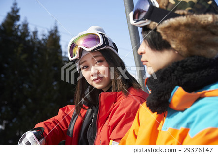 A couple riding a ski resort lift 29376147