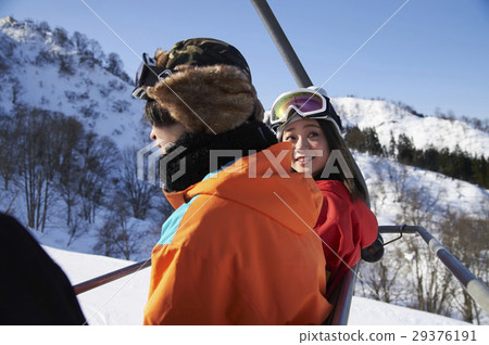 A couple riding a ski resort lift 29376191