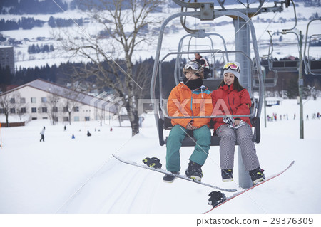 A couple riding a ski resort lift 29376309