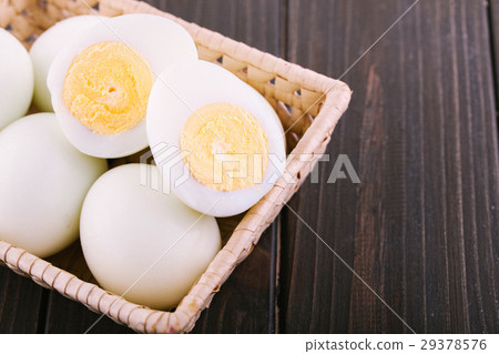 Cut boiled eggs lie in wooden besket on dark  29378576