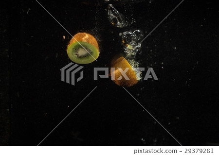 Juicy green halves of kiwi splash water  29379281