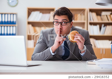 Hungry funny businessman eating junk food sandwich 29416352