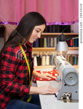 seamstress works on a sewing machine seamstress works on a sewing machine 29419316