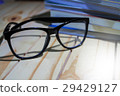 Glasses on wooden and books are in the background. 29429127