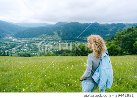 A young girl stands on top of a mountain in cloudy A young girl stands on top of a mountain in cloudy 29441981