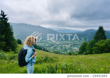 A young girl stands on top of a mountain in cloudy 29441983