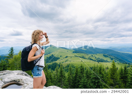 A young girl stands on top of a mountain in cloudy A young girl stands on top of a mountain in cloudy 29442001