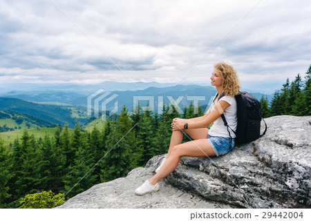 A young girl stands on top of a mountain in cloudy A young girl stands on top of a mountain in cloudy 29442004
