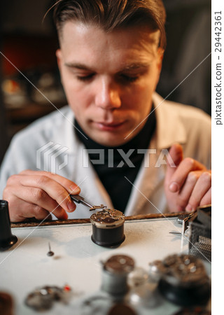 Watchmaker repair broken clockwork with tweezers 29442361