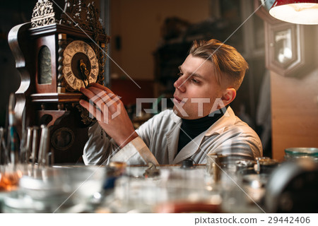 Watchmaker adjusts the mechanism of old wall clock 29442406