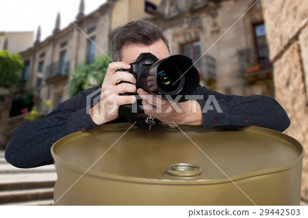 Photographer takes a picture leaning on barrel Photographer takes a picture leaning on barrel 29442503