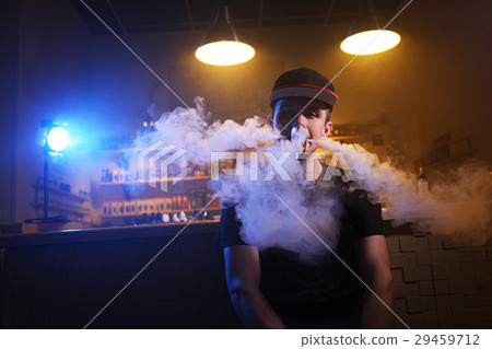 Vaping man holding a mod. A cloud of vapor at the 29459712