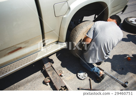 A man changing the wheel at the side of the road 29460751