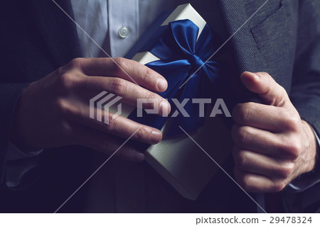 Man in suit opening a gift with blue ribbon Man in suit opening a gift with blue ribbon 29478324