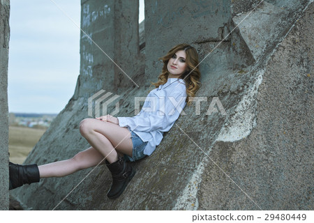 A Beautiful girl sits on an old bridge 29480449