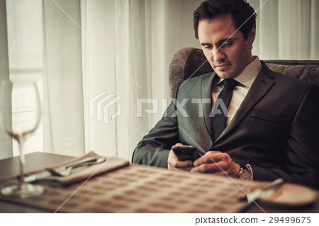 Confident man with smart phone in restaurant. 29499675
