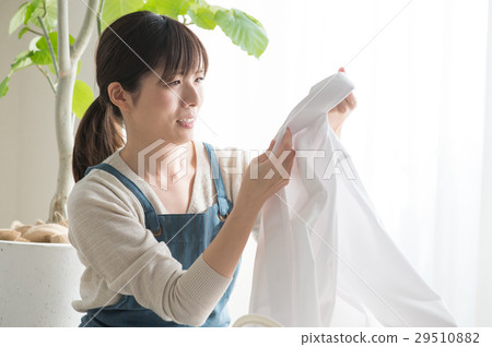 A woman looking at the collar of the laundry A woman looking at the collar of the laundry 29510882