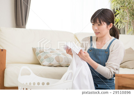 A woman looking at the collar of the laundry A woman looking at the collar of the laundry 29510896
